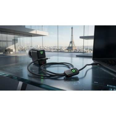 Pack Allure Ladegerät und Kabel auf Glastisch neben Laptop, im Hintergrund der Eiffelturm