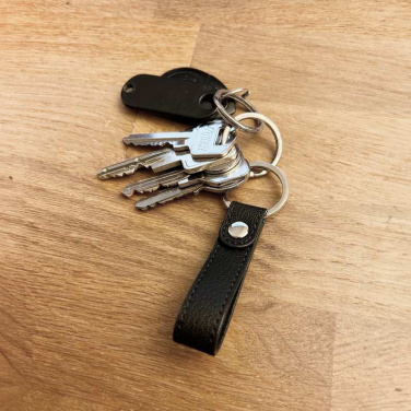 Black INÉ keyring with a bunch of keys on a wooden table