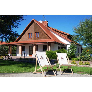 Two white deck chairs with a guesthouse logo in front of the house in sunshine