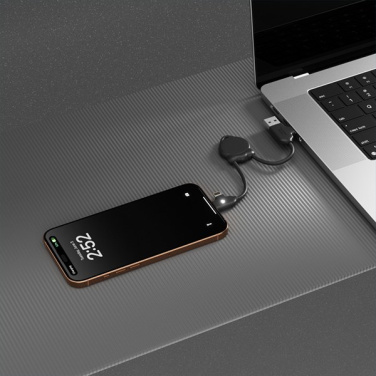 Juodas Octomini kabelis jungia nešiojamojo kompiuterio USB prievadą ir telefoną ant stalo
