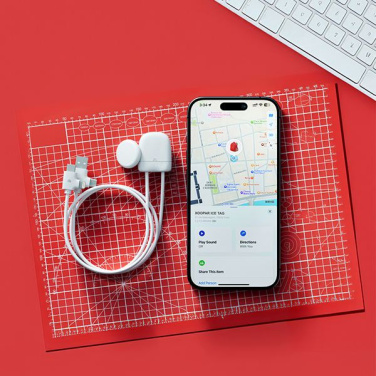 ICE-TAG un iPhone ar Find My lietotni uz sarkana griešanas paklāja blakus tastatūrai