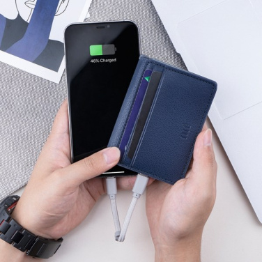 Zils INÉ The Wallet rokā ar vadu uzlādē viedtālruni, ekrānā 46% uzlādēts