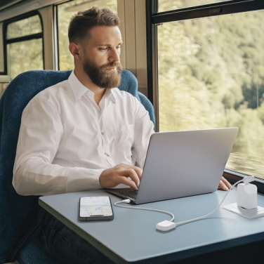 Man arbetar på laptop i ett tåg, ICE-TAG-kabel och mobil på bordet
