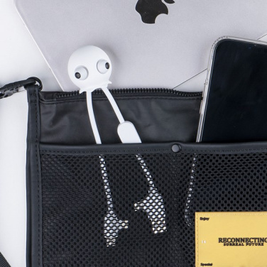 Jelly Mini-kabel tittar upp ur fickan på en svart datorväska bredvid telefon och laptop